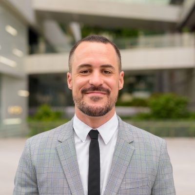 Portrait of handsome Hispanic bald bearded businessman wearing suit in the city streets outdoors